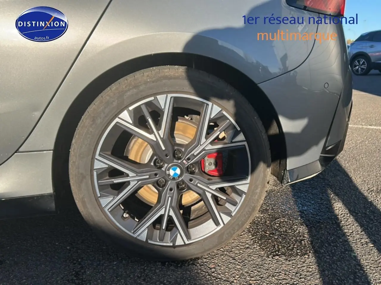 Gros plan sur la roue arrière droite d'une BMW Série 1 gris Skyscraper avec jante 18 pouces bicolore en Y.