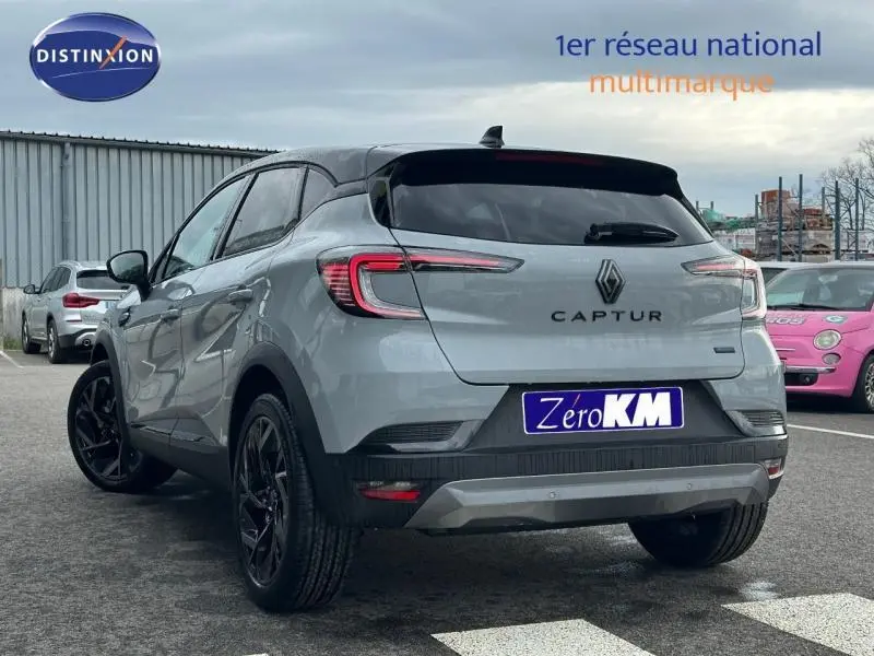 Vue 3/4 arrière d'un Renault Captur 2026 gris Rafale avec toit noir étoilé et jantes noires, version hybride esprit Alpine.