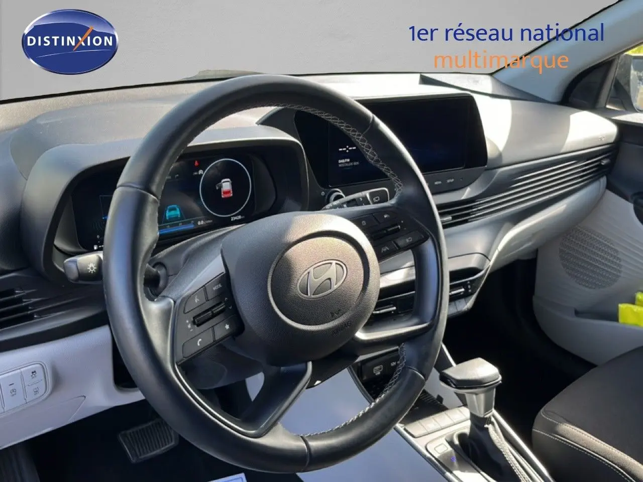 Vue intérieure centrée sur le volant cuir et le tableau de bord clair de la Hyundai i20 2025 gris Aurora Metal.