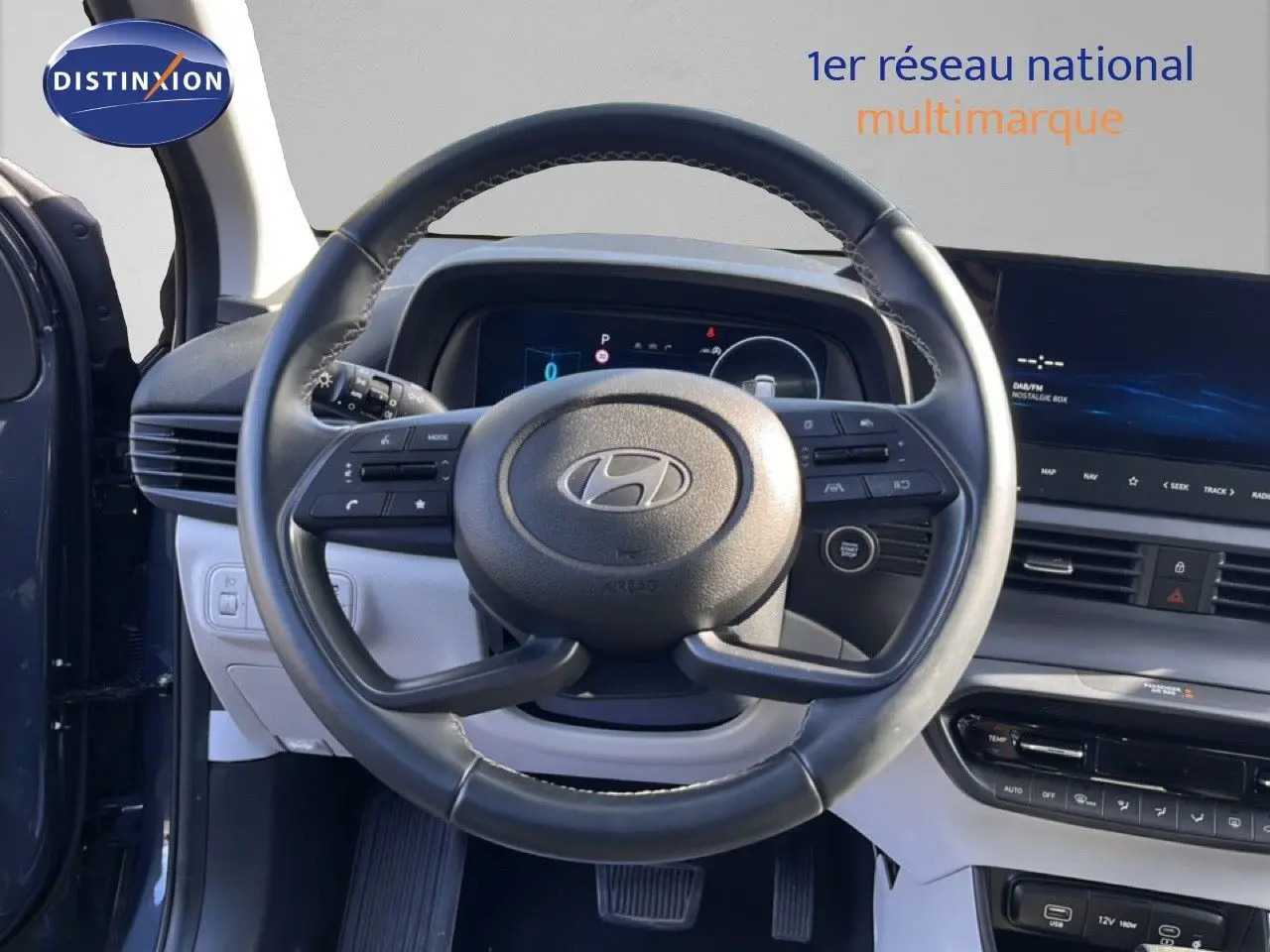 Vue intérieure centrée sur le volant cuir multifonction de la Hyundai i20 2025, avec tableau de bord digital et écran tactile.
