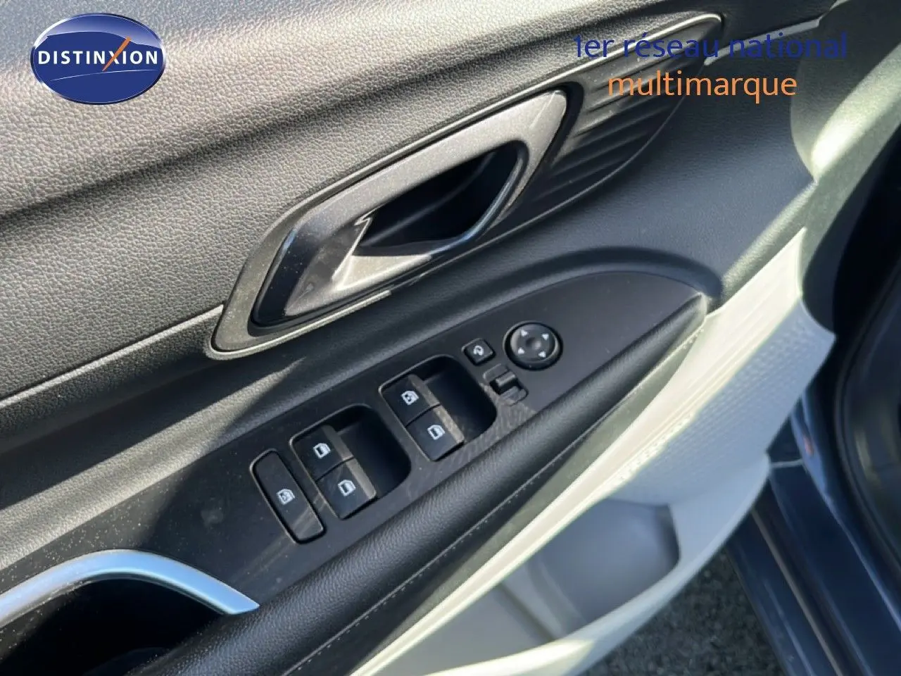 Gros plan sur la commande des vitres et la poignée intérieure côté conducteur d'une Hyundai i20 gris Aurora Metal.