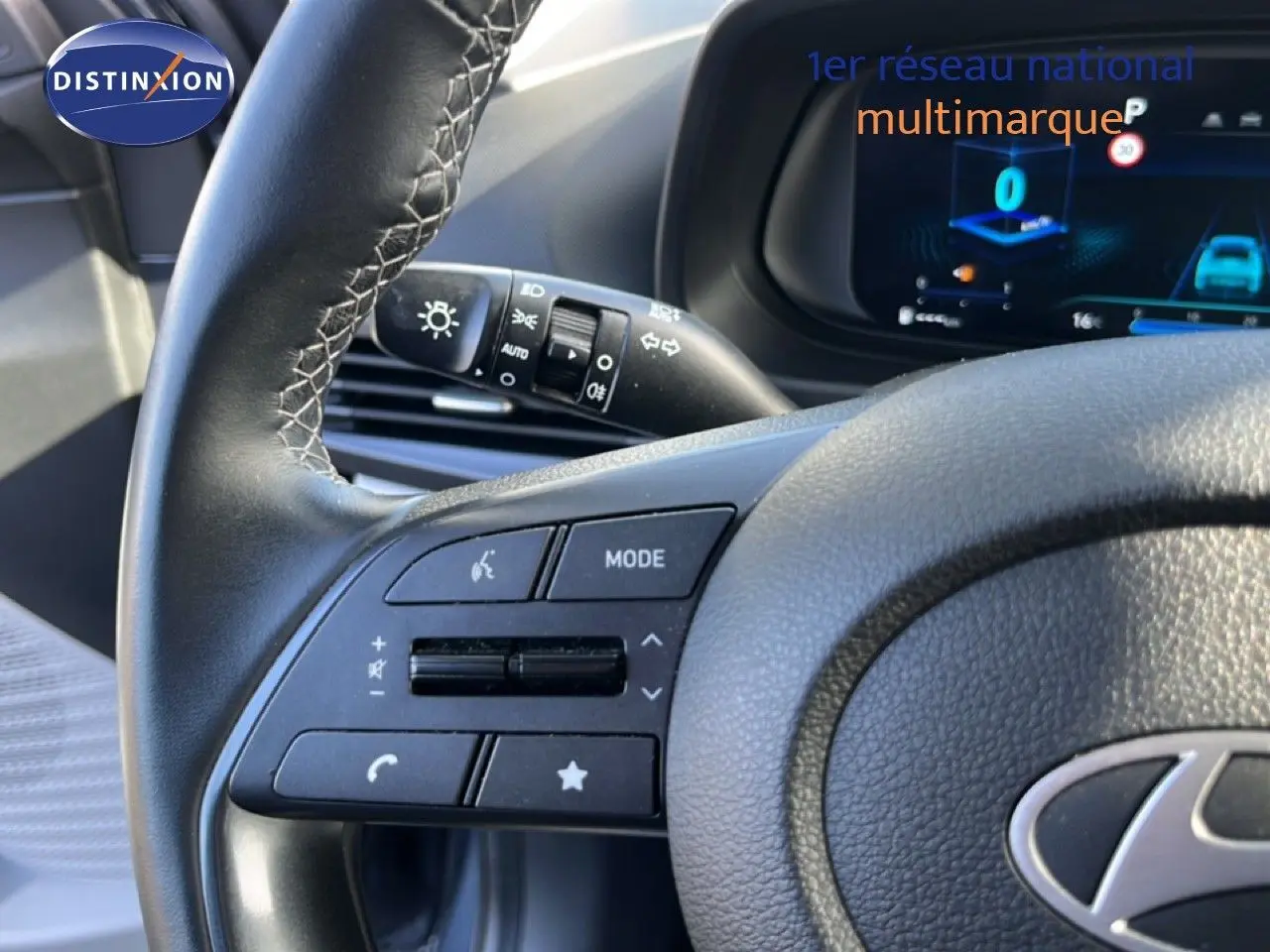 Gros plan sur le volant gris noir de la Hyundai i20 2025, avec commandes multifonctions et tableau de bord digital en arrière-plan.