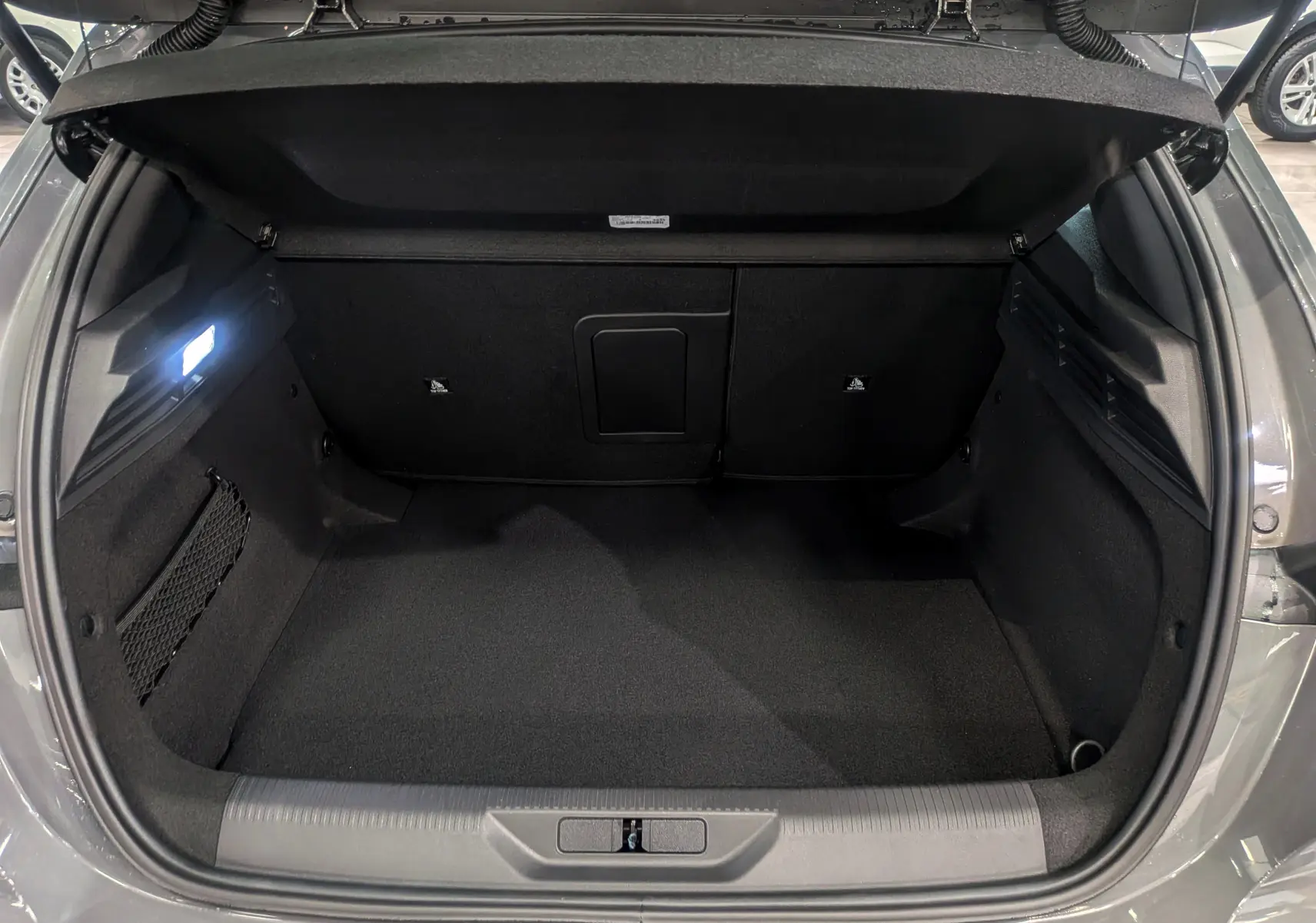 Coffre ouvert de la Peugeot 308 GT Exclusive gris Sélénium, montrant un espace de chargement propre et bien éclairé.