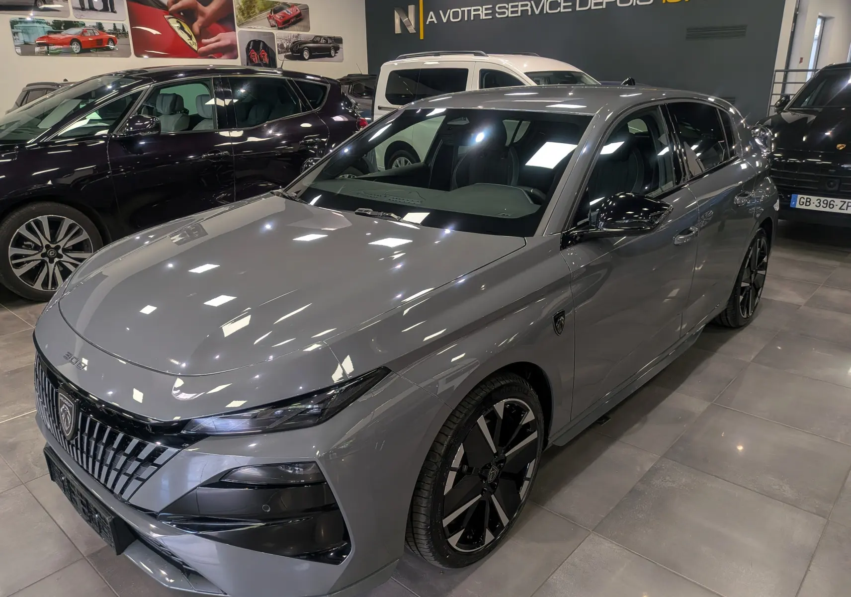 Vue 3/4 avant droite d'une Peugeot 308 gris Sélénium avec jantes noires bicolores et calandre distinctive en concession.