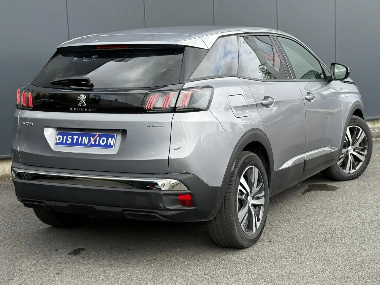 Vue 3/4 arrière droite d’un Peugeot 3008 gris Artense avec jantes alliage bi-ton et badge Hybrid visible sur l’aile.