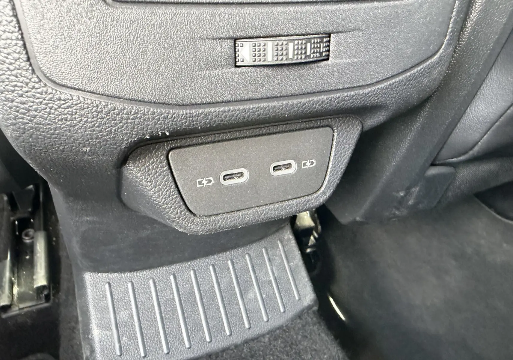Gros plan sur les ports USB-C de recharge situés à l'arrière de la console centrale d'un Volkswagen T-Roc gris.