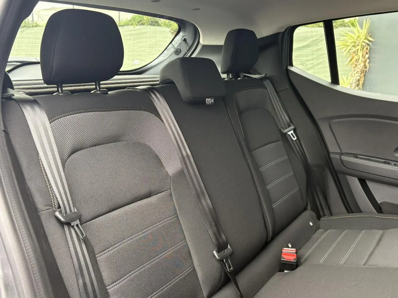 Vue intérieure de la banquette arrière noire du Dacia Sandero Stepway 2025, avec ceintures et appuie-têtes visibles.