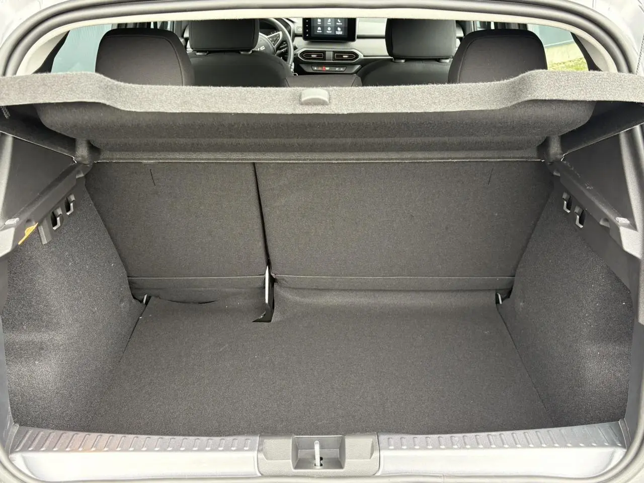 Coffre ouvert du Dacia Sandero Stepway gris Schiste, vue arrière montrant l'espace de chargement et les sièges arrière.