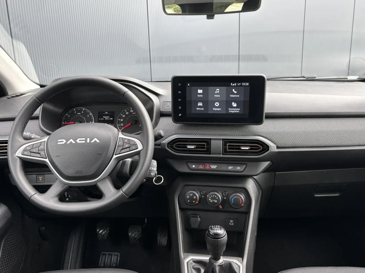 Vue intérieure du tableau de bord et volant gris de la Dacia Sandero Stepway 2025 avec écran tactile central et boîte manuelle.