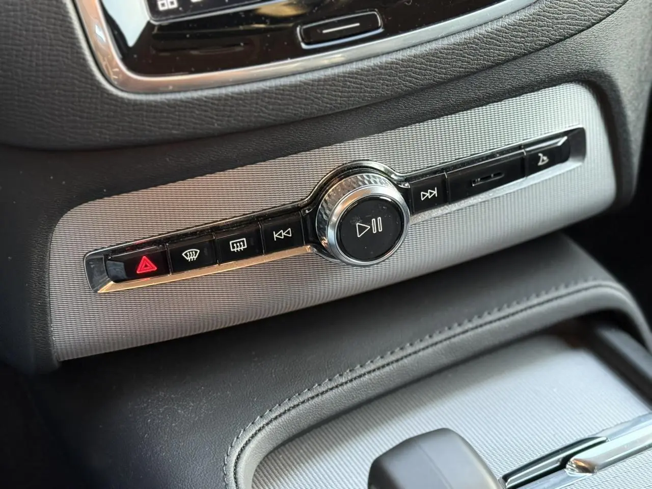 Gros plan sur la commande multimédia centrale du Volvo XC90 blanc Crystal 2024 avec finition Chrome et détails noirs.