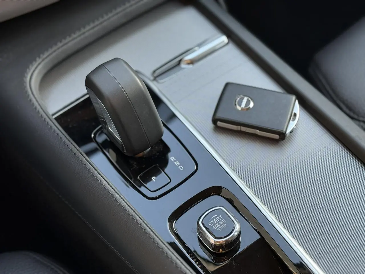 Gros plan sur la console centrale du Volvo XC90 blanc avec levier de vitesse et clé électronique.