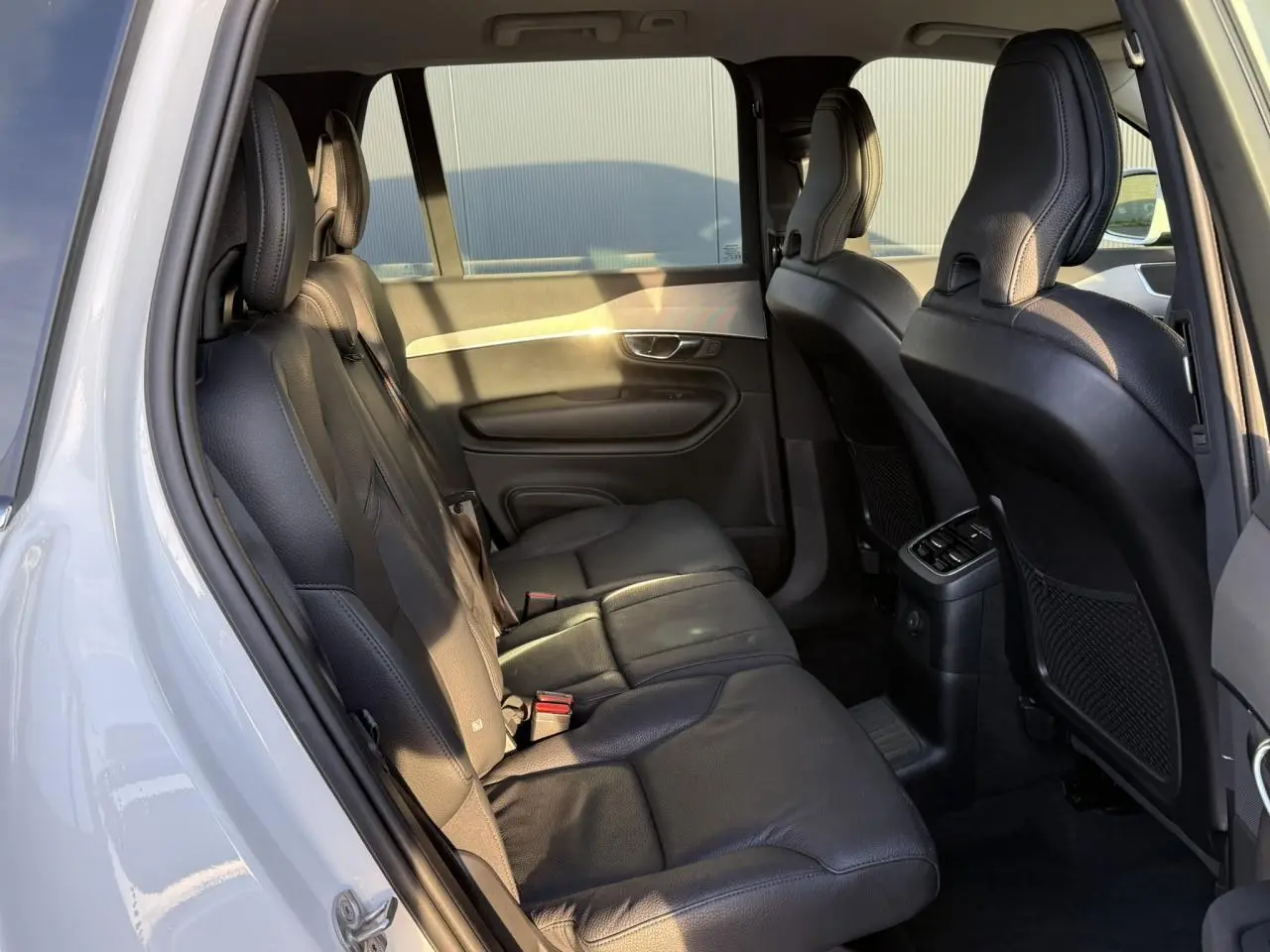 Vue intérieure côté gauche sur la banquette arrière en cuir noir du Volvo XC90 blanc Crystal 2024.