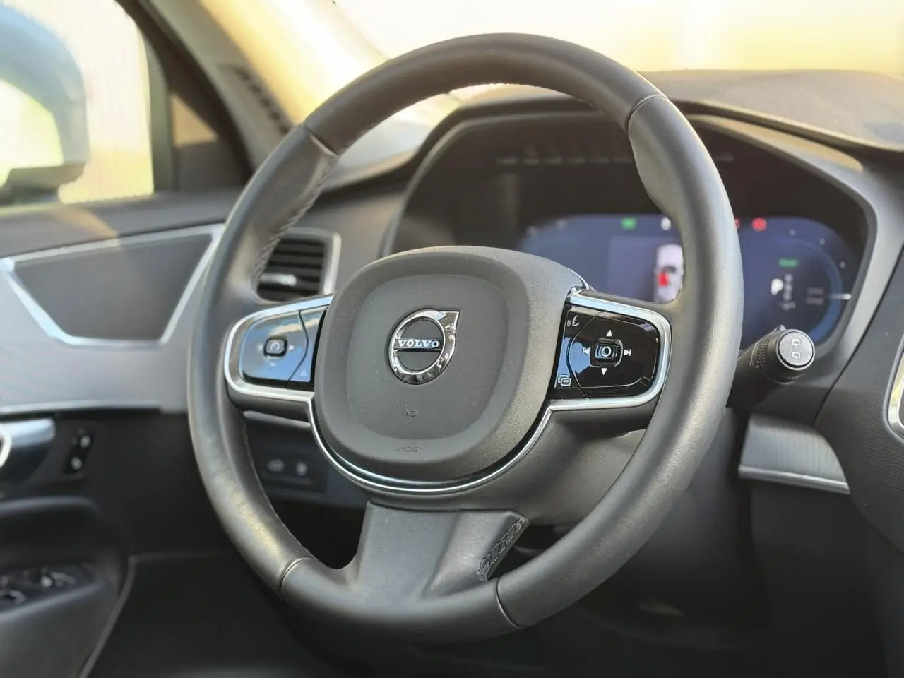 Volant en cuir noir avec commandes intégrées et logo Volvo au centre dans l'habitacle du XC90 2024.