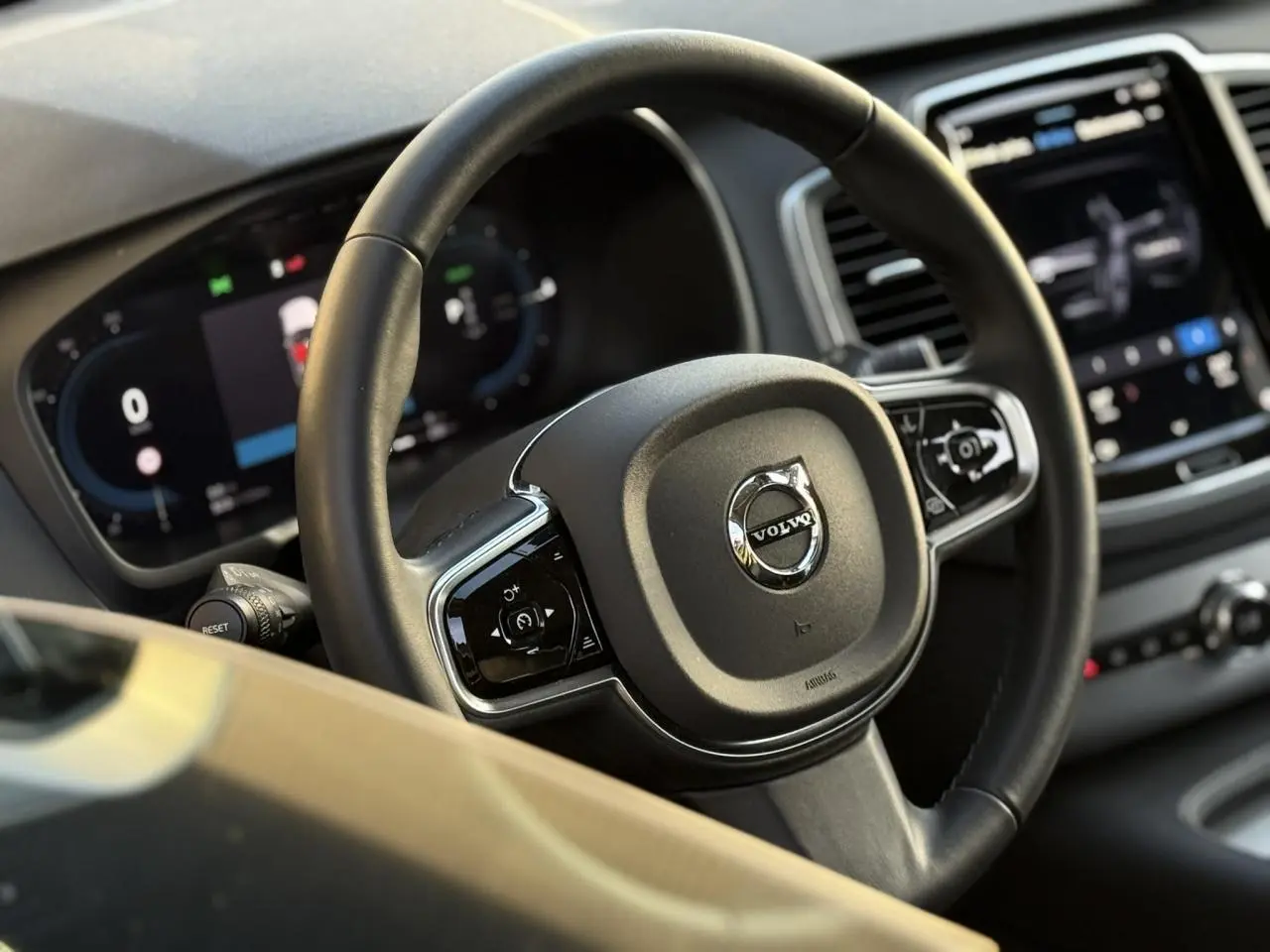 Volant en cuir noir avec logo Volvo au centre, tableau de bord digital et écran tactile du Volvo XC90 T8 hybride 2024.