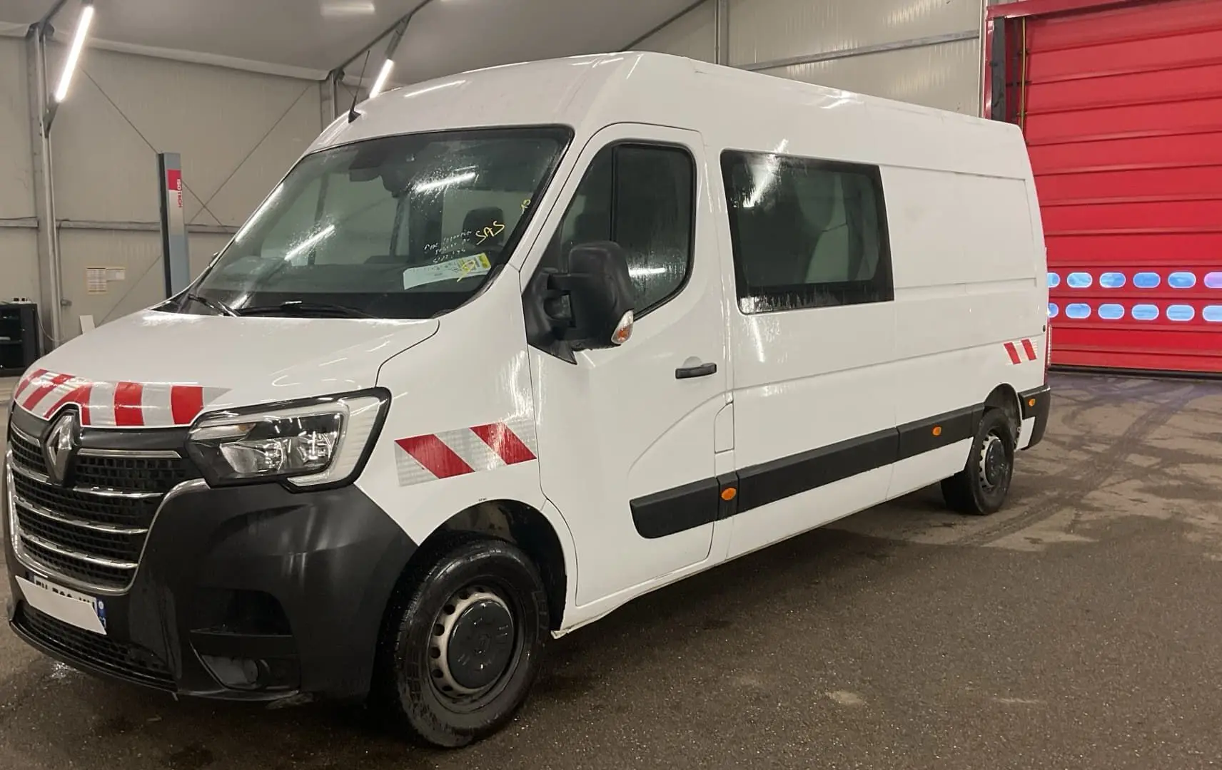 Renault Master cabine approfondie blanc vu en 3/4 avant droit avec bandes réfléchissantes rouges et blanches.