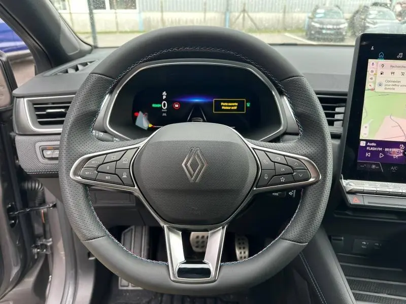 Vue intérieure centrée sur le volant du Renault Captur 1.8 E-Tech hybride 2026, avec tableau de bord numérique et écran tactile.