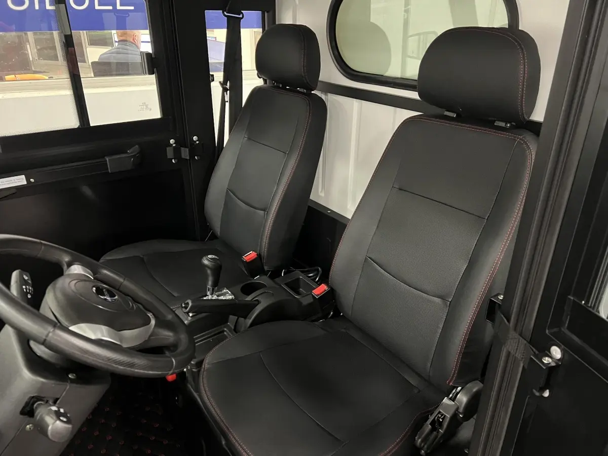 Vue intérieure côté conducteur du Liberty L7e H2 Cargo 2025, sièges noirs avec surpiqûres rouges et volant 3 branches.