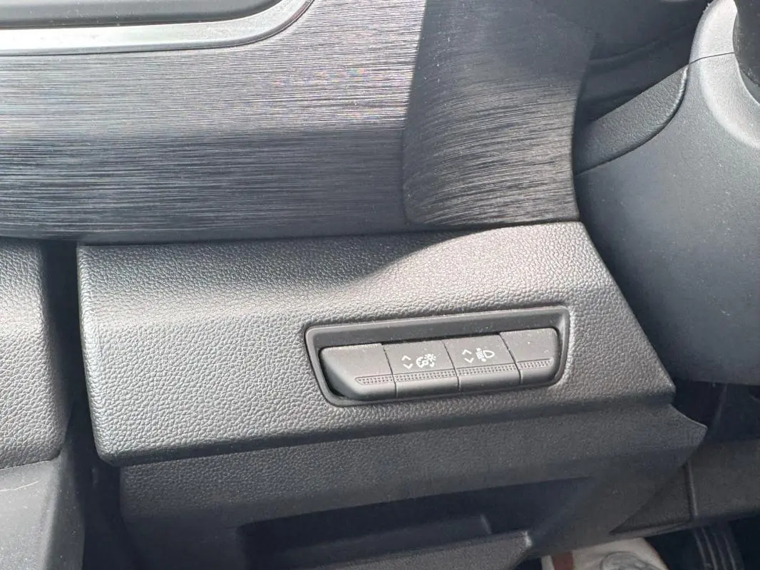 Détail intérieur montrant les commandes de réglage des feux et du tableau de bord du Renault Trafic Fourgon gris foncé.