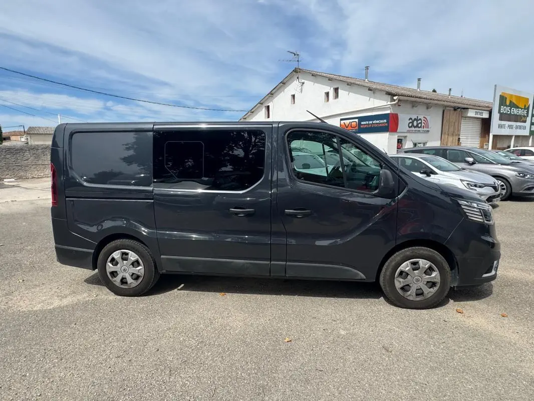 Vue latérale droite d’un Renault Trafic Fourgon gris foncé avec vitres surteintées, porte latérale coulissante et jantes acier.