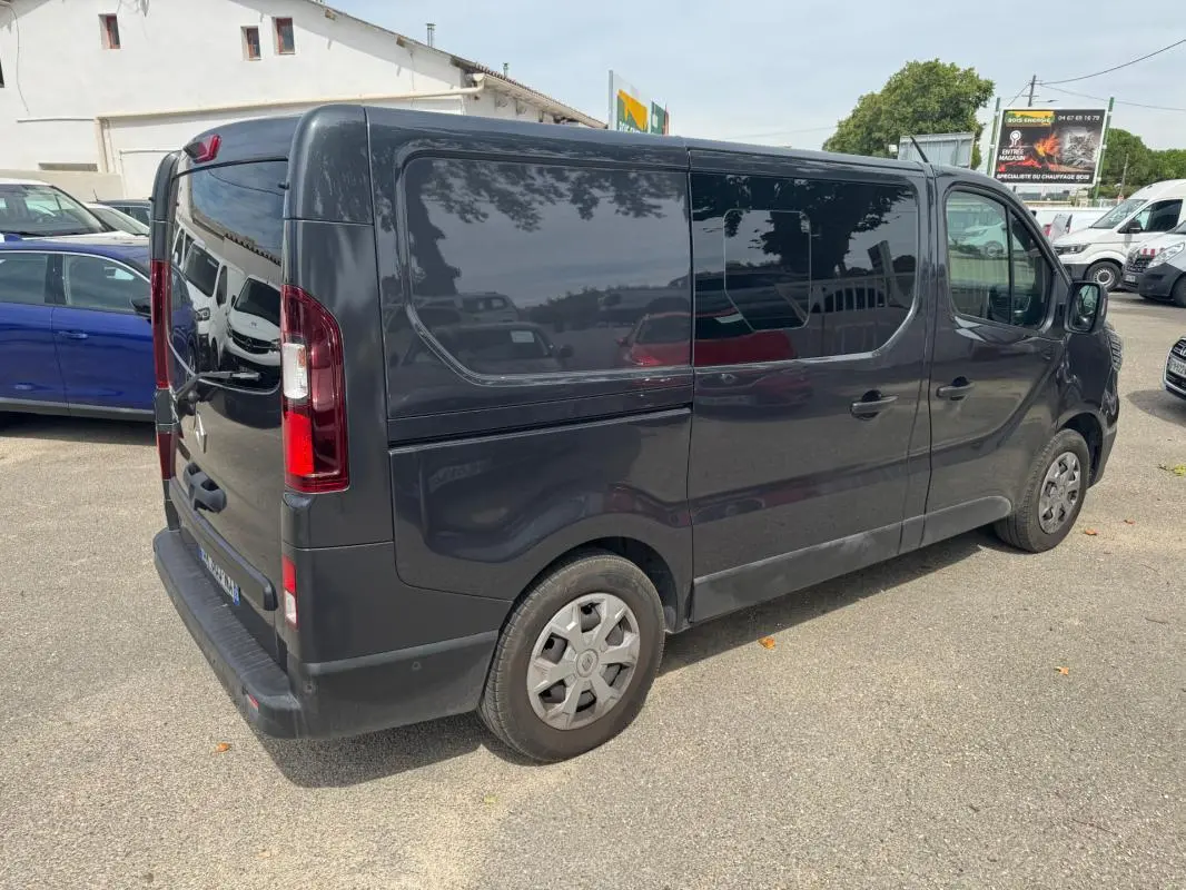 Vue 3/4 arrière droite d’un Renault Trafic fourgon gris foncé avec vitres surteintées et porte latérale fermée.