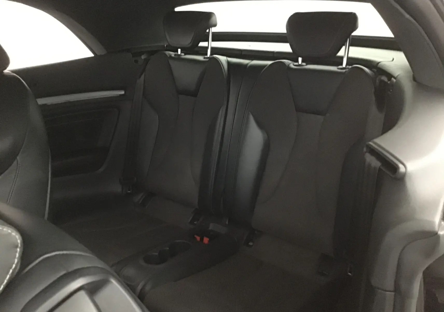 Vue intérieure arrière des sièges noirs en cuir de l'Audi A3 Cabriolet 2020, avec accoudoir central et appuie-têtes.