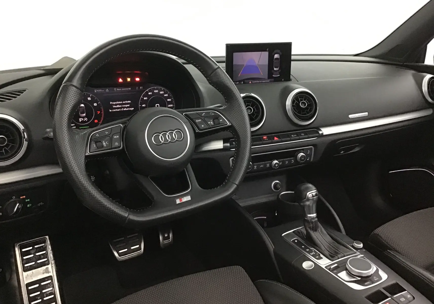 Vue intérieure de l'Audi A3 Cabriolet 2020, tableau de bord noir avec volant sport et écran central affichant la caméra de recul.