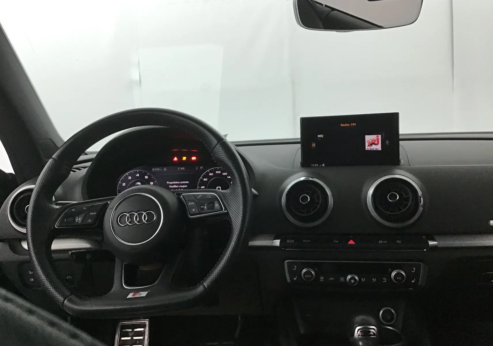 Vue intérieure du tableau de bord noir de l'Audi A3 Cabriolet 2020, avec volant sport et écran central allumé.