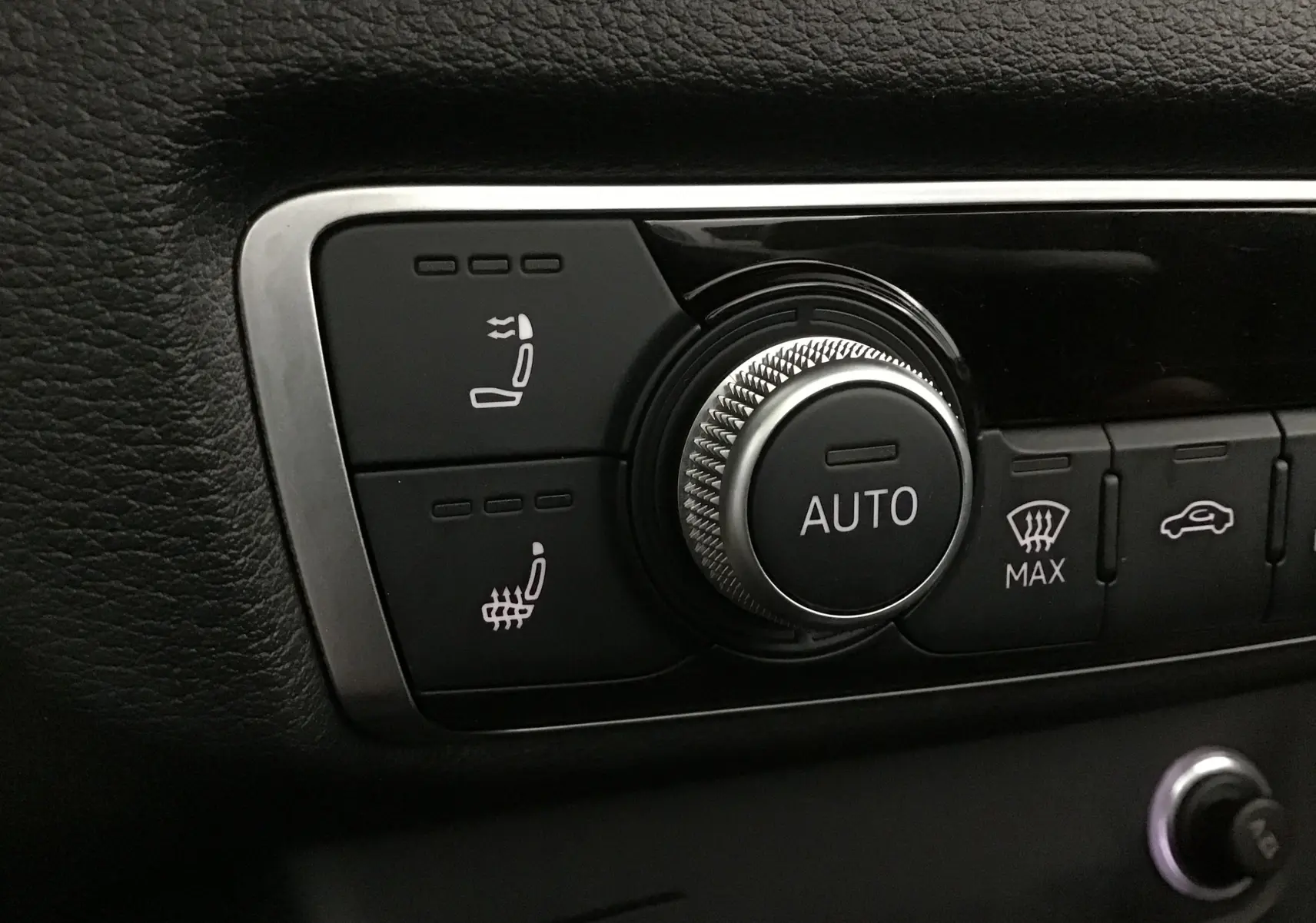 Gros plan sur les commandes de chauffage de siège et ventilation avec molette Auto dans l’Audi A3 Cabriolet noire 2020.
