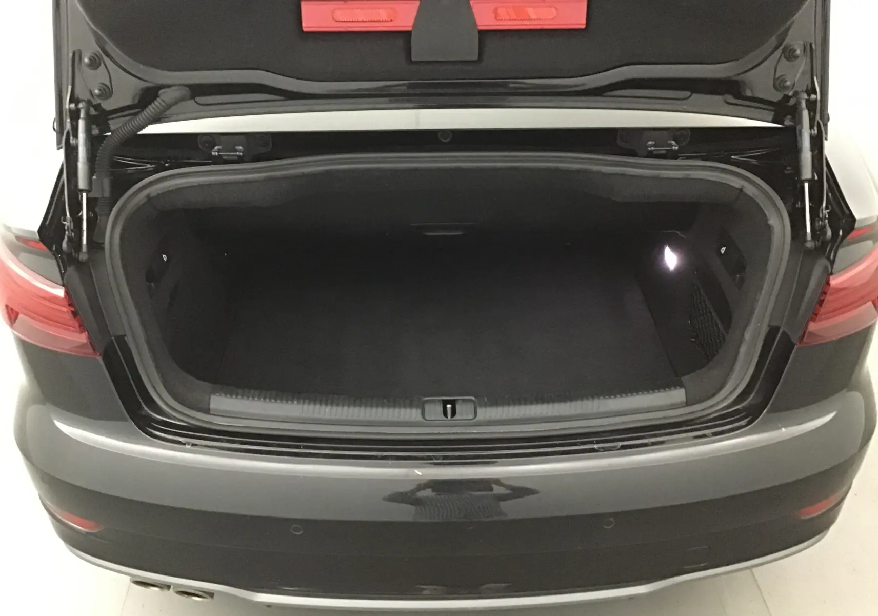Coffre ouvert vu de l'arrière d'une Audi A3 Cabriolet noir 2020, montrant l'espace de chargement vide et éclairé.