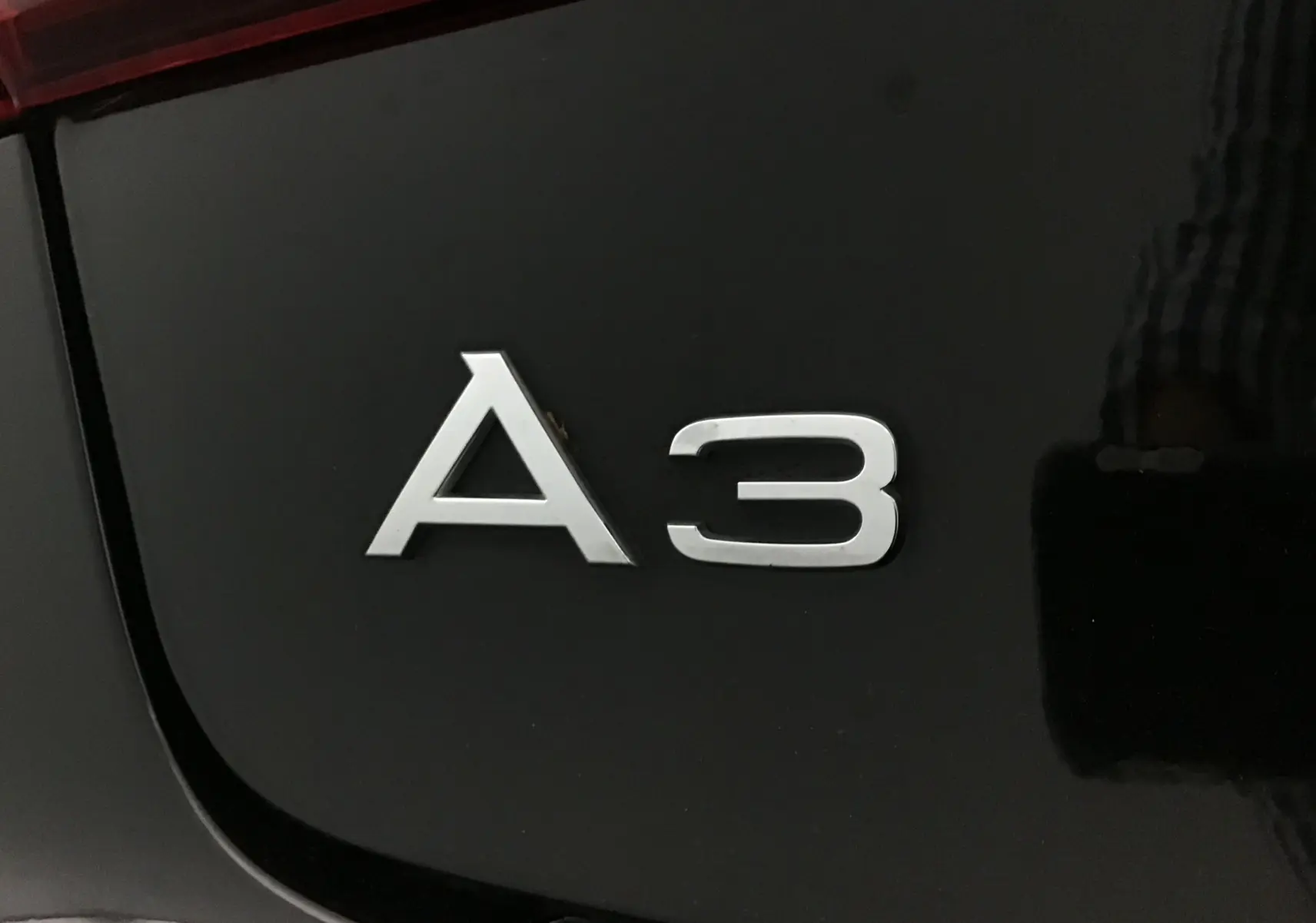 Gros plan sur l'emblème A3 argenté sur la carrosserie noire brillante d'une Audi A3 Cabriolet 2020