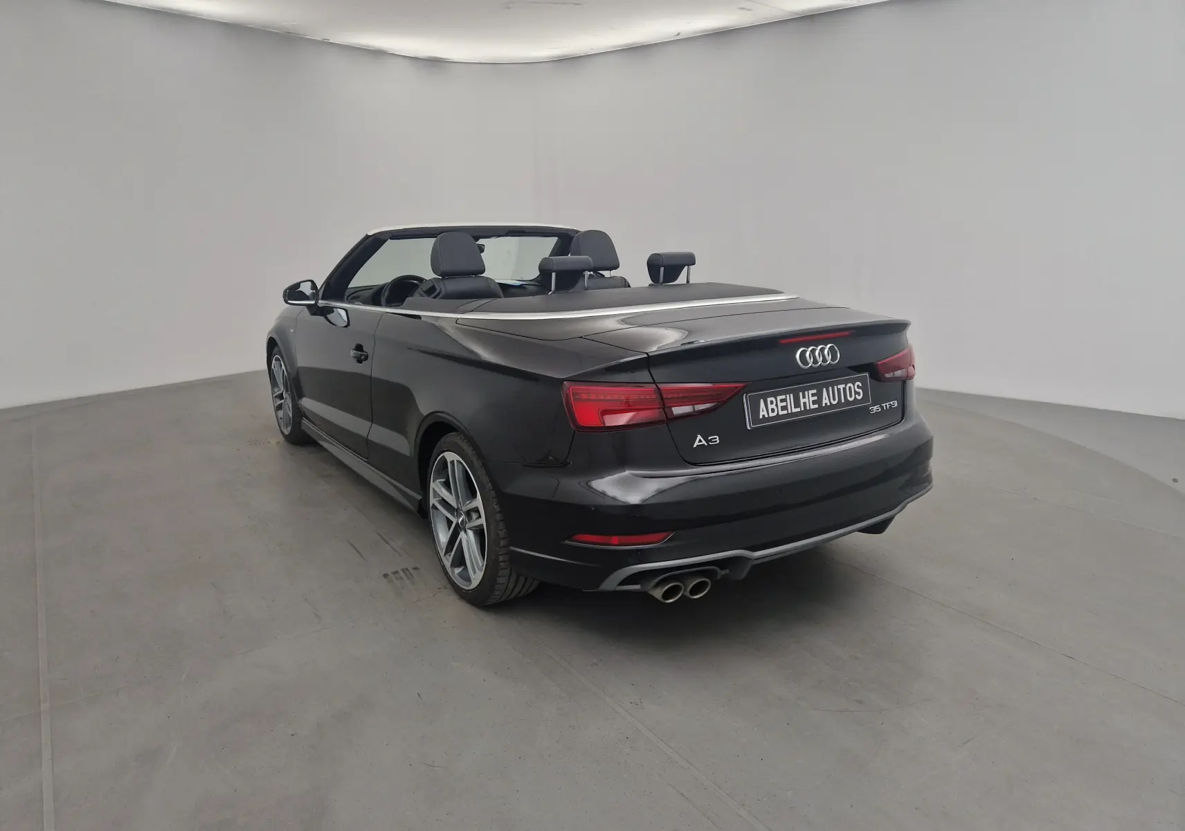 Audi A3 Cabriolet noir vue 3/4 arrière droit avec capote électrique et double sortie d'échappement chrome.