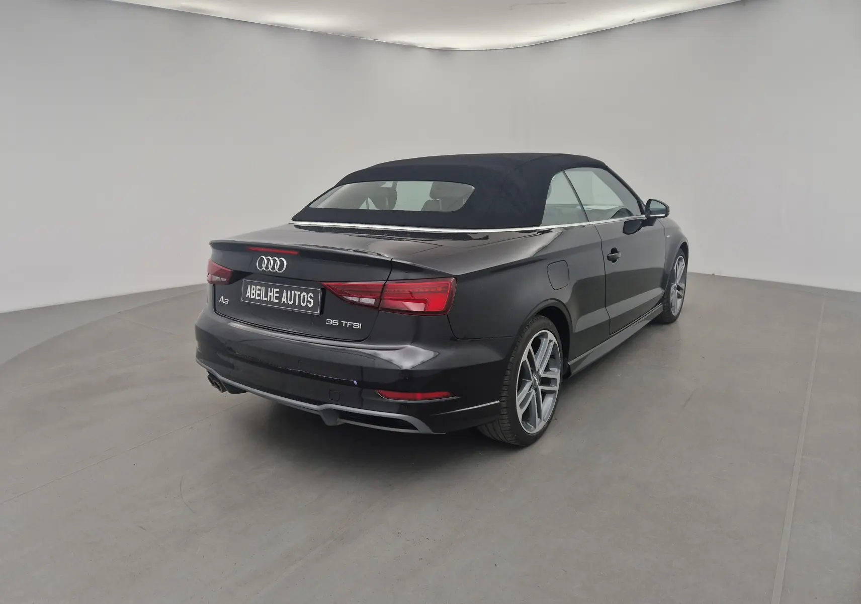 Audi A3 Cabriolet noir vue 3/4 arrière droit avec capote électrique en toile fermée dans un studio blanc.