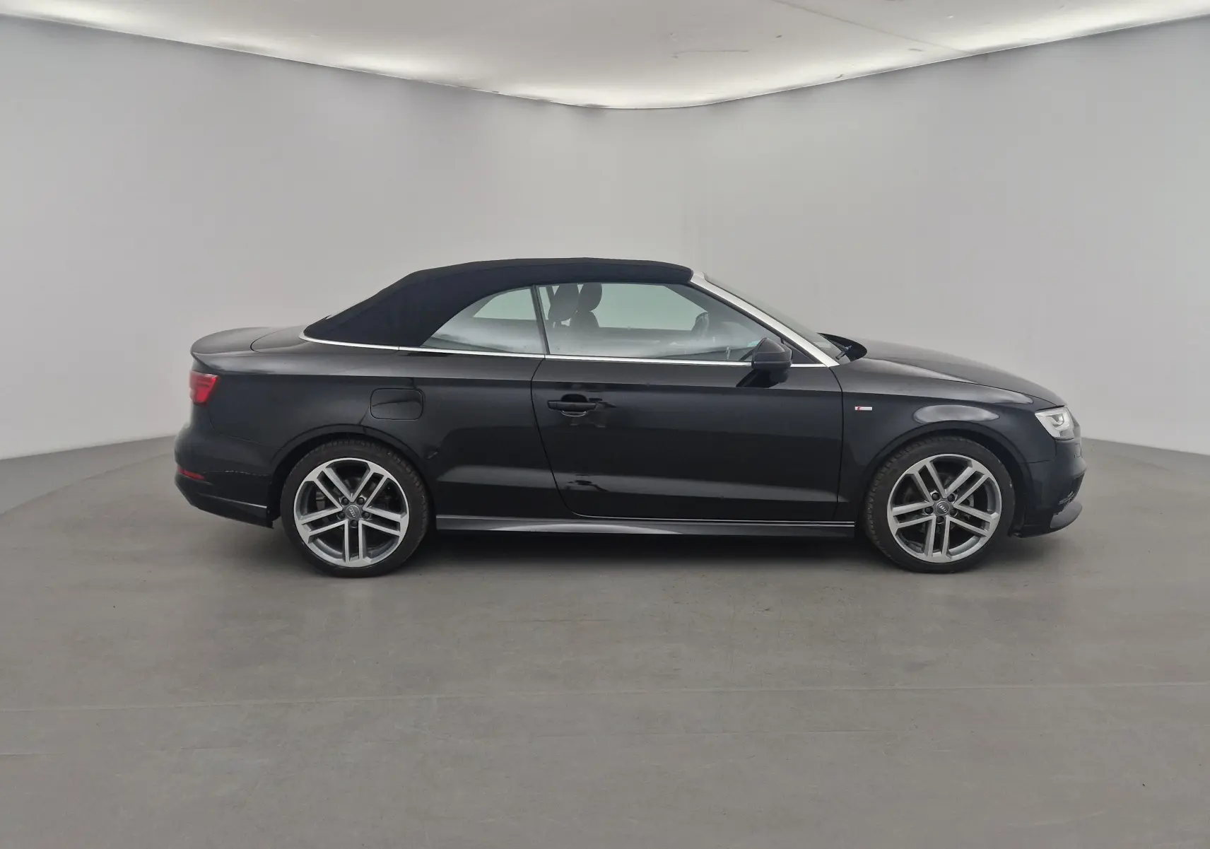 Profil côté gauche d'une Audi A3 Cabriolet noire 2020 avec capote électrique en toile fermée et jantes alliage 18 pouces.