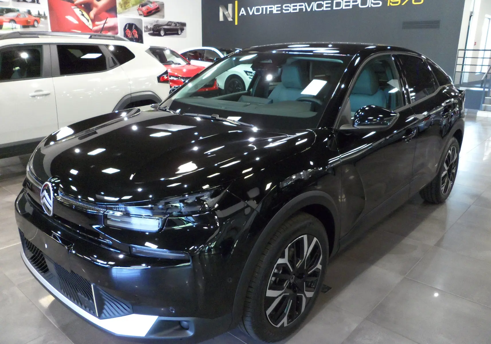 Citroën C4 Hybride noir Perla vue 3/4 avant droit en intérieur avec jantes stylées et calandre lumineuse.