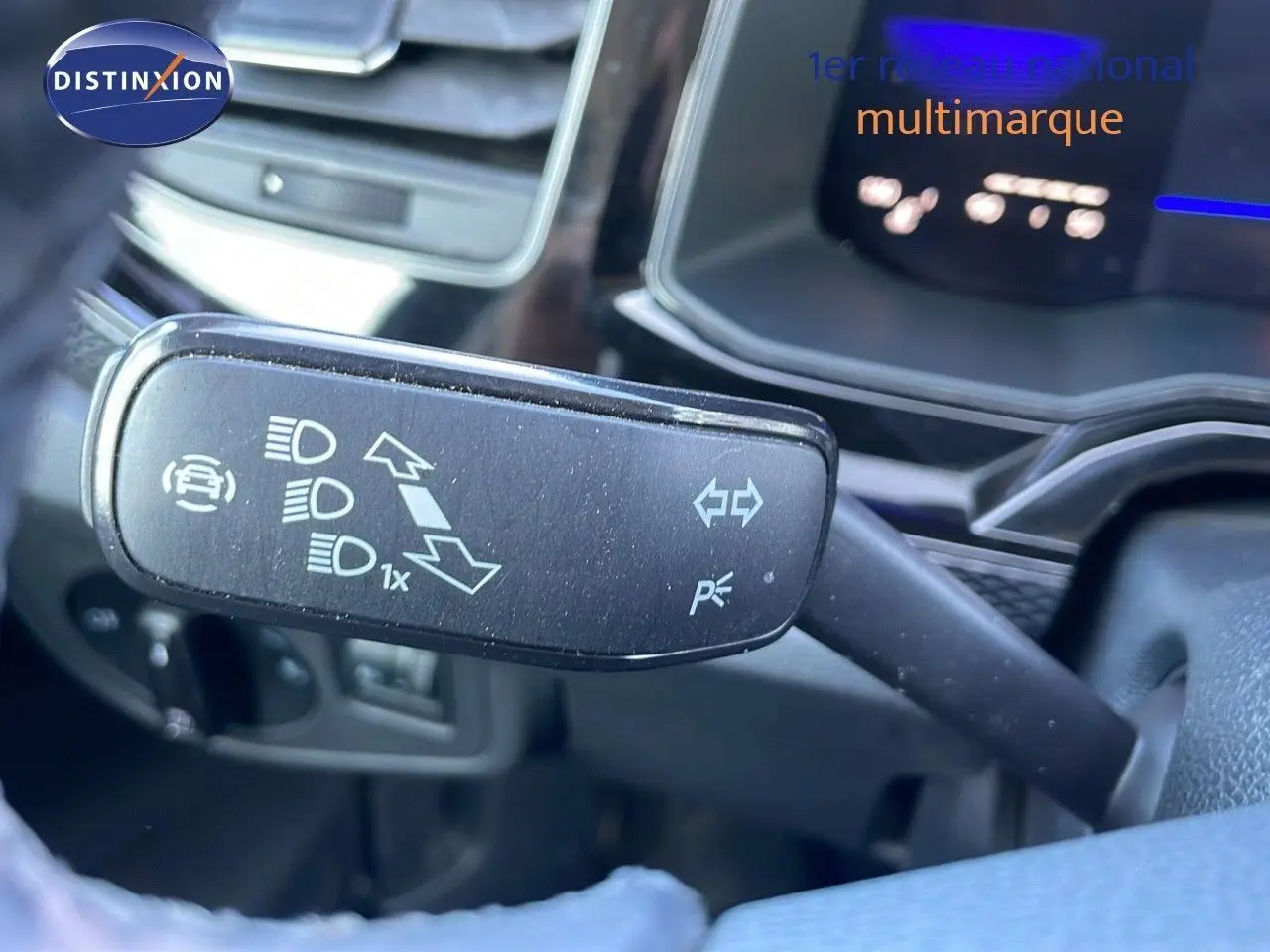 Gros plan sur la commande des clignotants et feux d'un Volkswagen Taigo gris cendre, tableau de bord en arrière-plan.