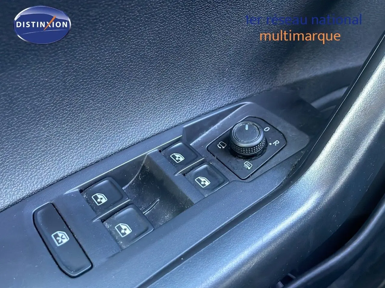 Gros plan sur les commandes des vitres électriques et réglage des rétroviseurs côté conducteur d'un Volkswagen Taigo gris cendre.