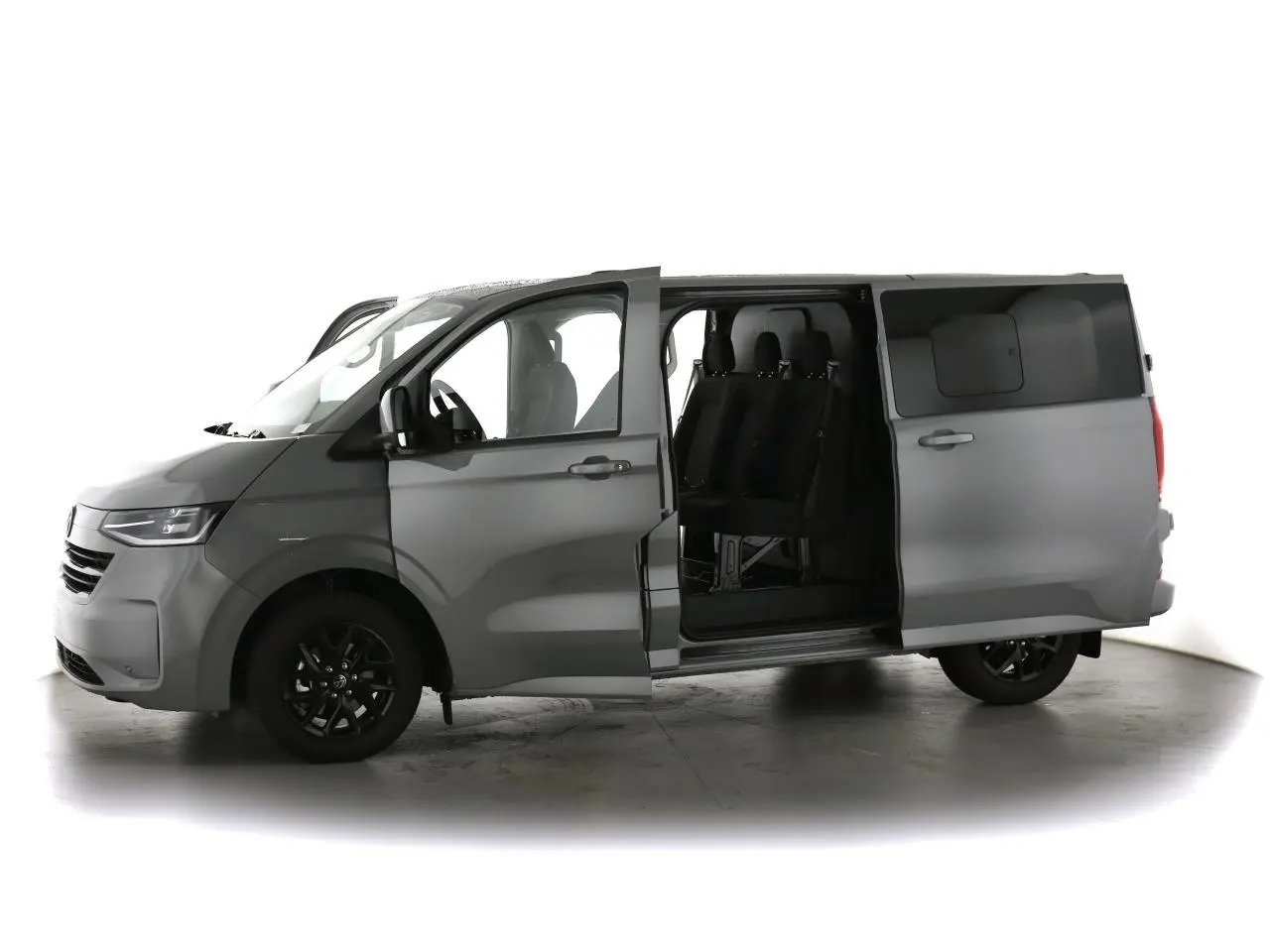 Vue de profil gauche d'un Volkswagen Transporter T7 gris Stone avec porte coulissante ouverte révélant les sièges arrière noirs.