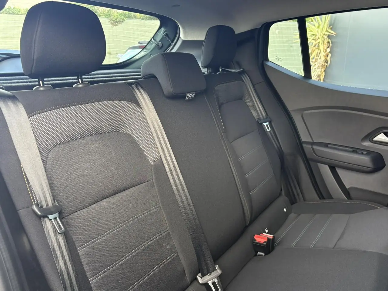Vue intérieure de la banquette arrière noire du Dacia Sandero Stepway 2025 avec ceintures et appuie-têtes visibles.