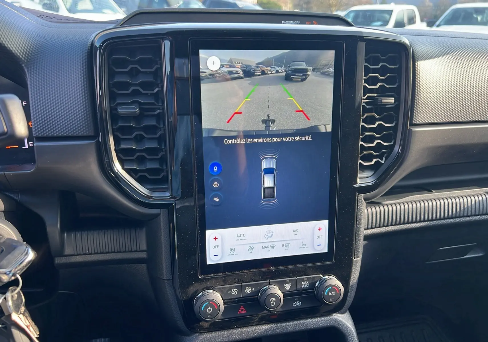 Vue rapprochée de l'écran central tactile du Ford Ranger 2025 blanc glacier, affichant la caméra de recul et les commandes climatisation.