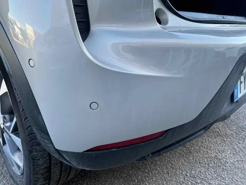 Gros plan sur le pare-chocs arrière gris Platinium du DS3 Crossback E-Tense avec capteurs de stationnement visibles.