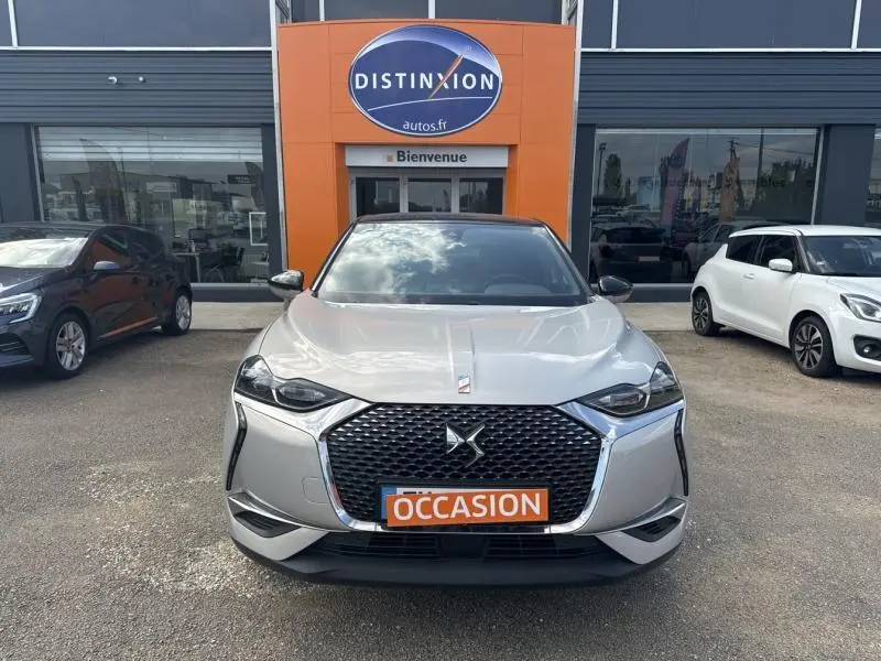 Vue avant d'un DS3 Crossback E-Tense gris Platinium avec toit noir, calandre DS Wings chromée et plaque "OCCASION" orange.