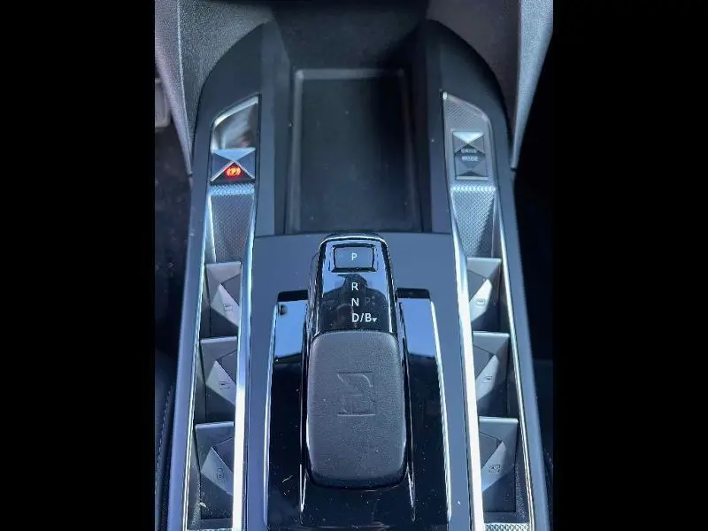 Vue rapprochée de la console centrale noire brillante du DS3 Crossback E-Tense avec levier de vitesse automatique et boutons latéraux.