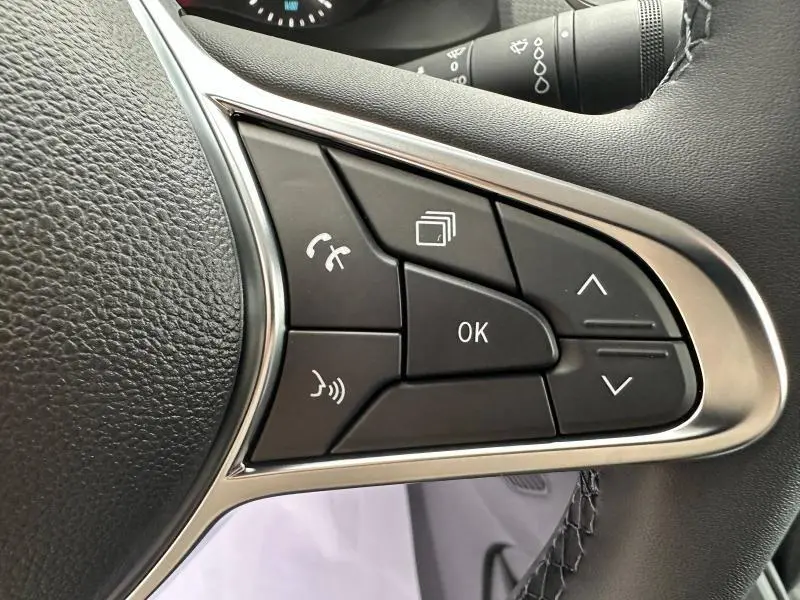 Gros plan sur les commandes multifonctions du volant cuir noir du Nissan Townstar blanc minéral 2024 électrique.