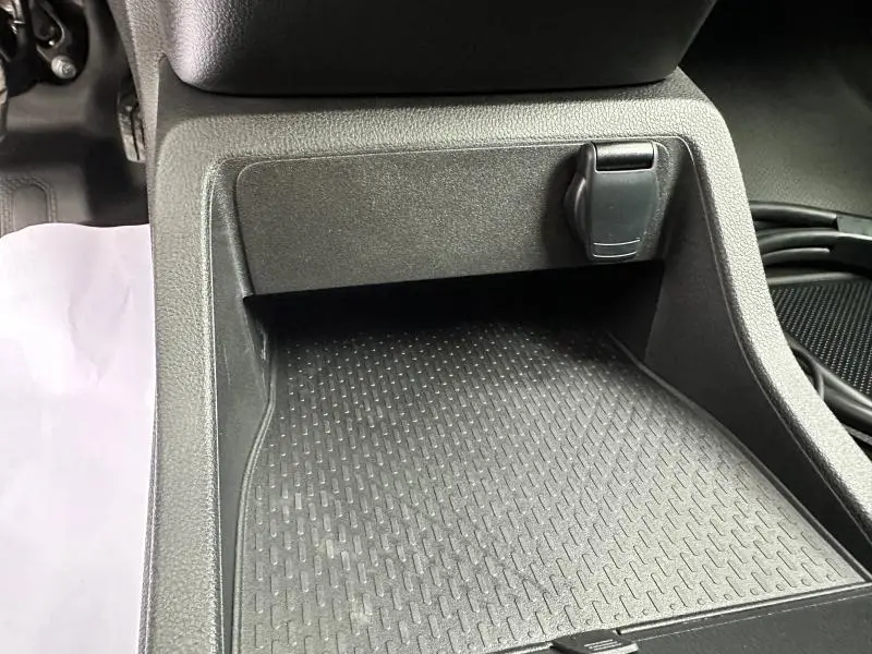 Gros plan sur le rangement central avant noir avec prise 12V dans le Nissan Townstar L1 EV blanc minéral 2024