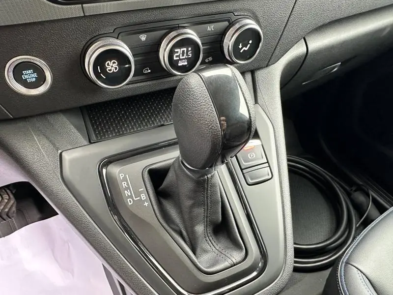 Gros plan sur la console centrale du Nissan Townstar électrique 2024 montrant le levier de vitesses automatique et les commandes de climatisation.