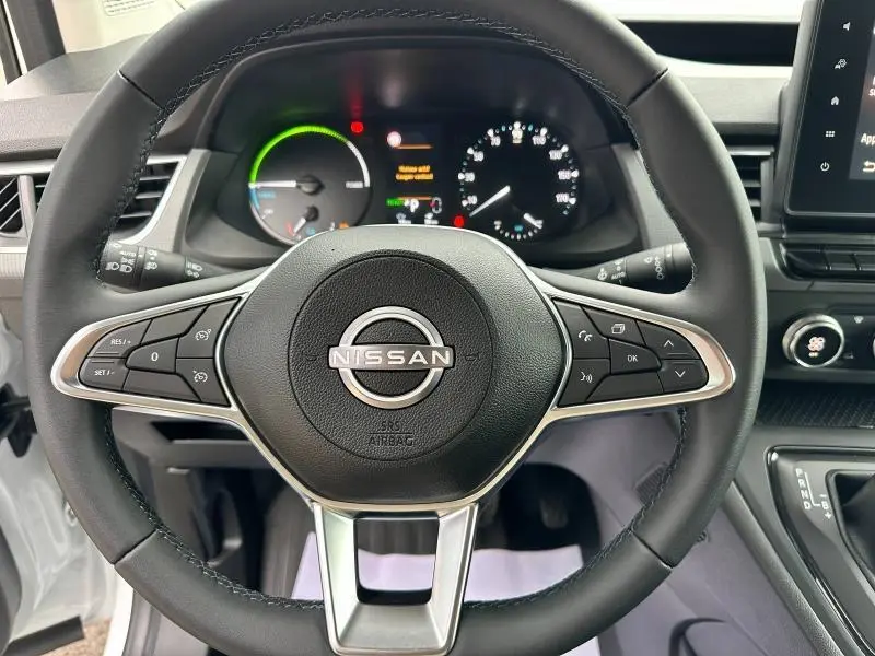Vue rapprochée du volant cuir Nissan Townstar blanc minéral 2024 avec commandes intégrées et tableau de bord numérique.