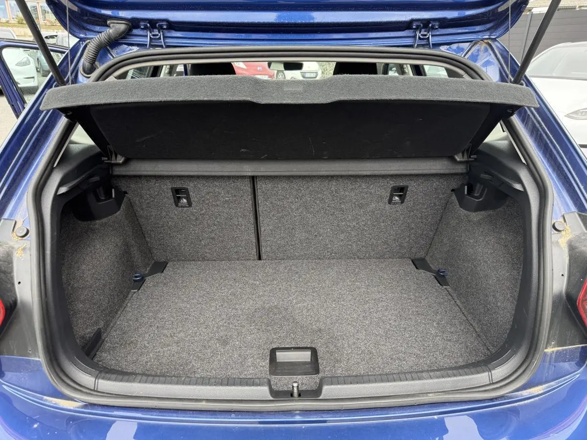 Coffre ouvert d'une Volkswagen Polo bleu 3/4 arrière, montrant un espace de chargement propre et spacieux.