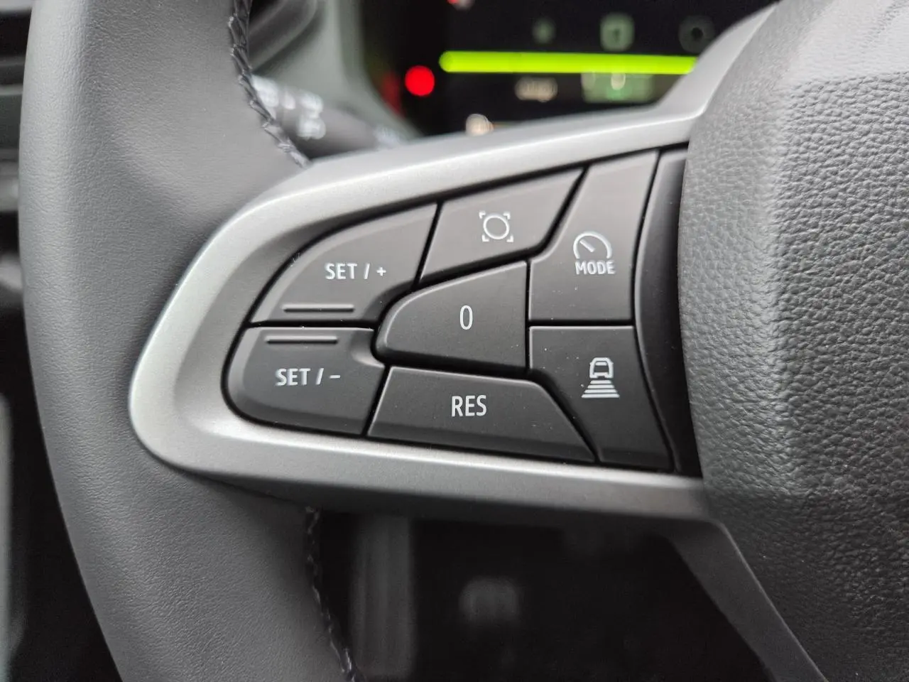 Gros plan sur les commandes au volant à gauche du Dacia Bigster 2025 blanc glacier, avec boutons de régulateur de vitesse et mode conduite.