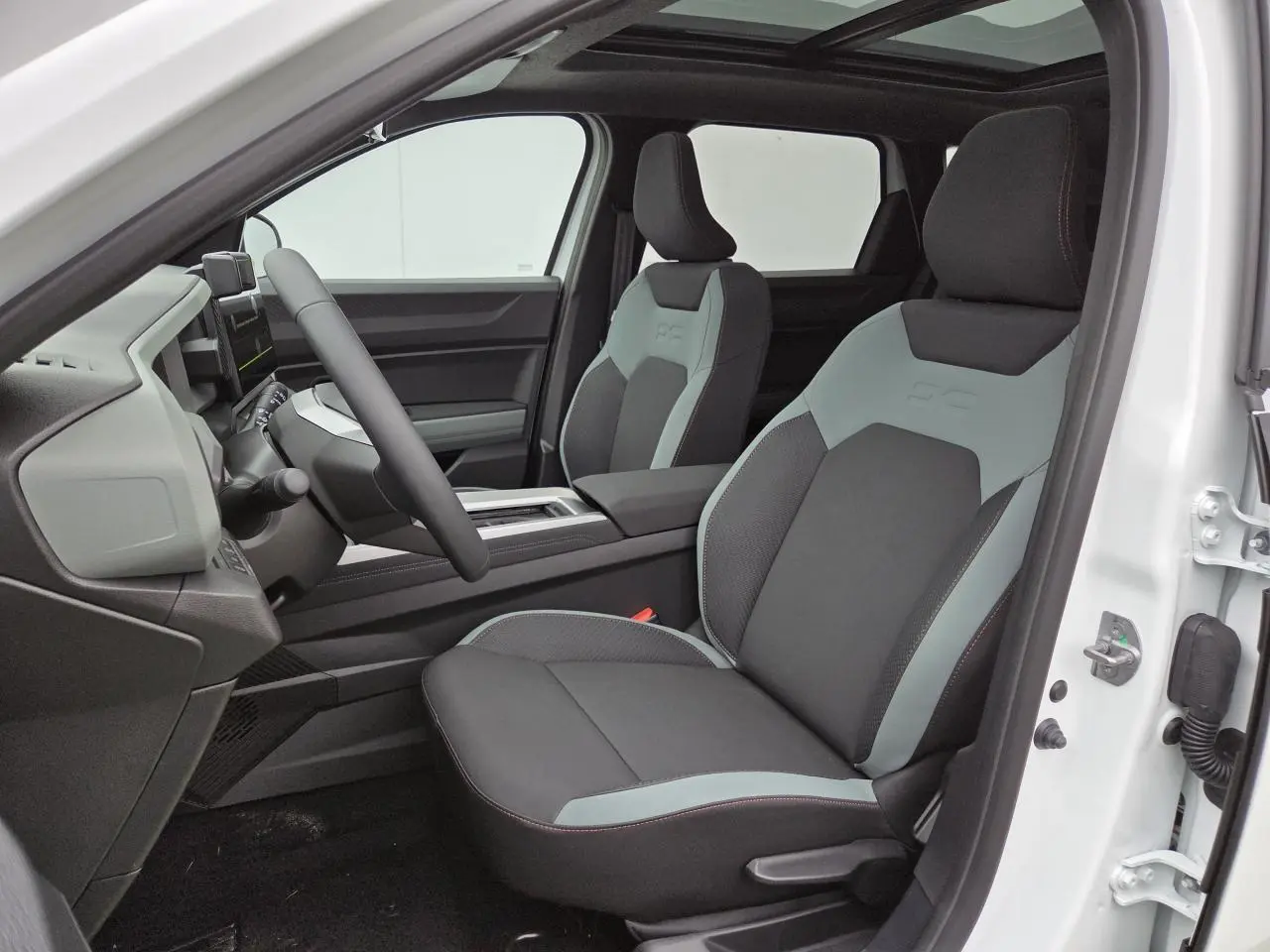 Vue intérieure côté conducteur du Dacia Bigster blanc glacier 2025 avec sièges bicolores et toit panoramique ouvrant.