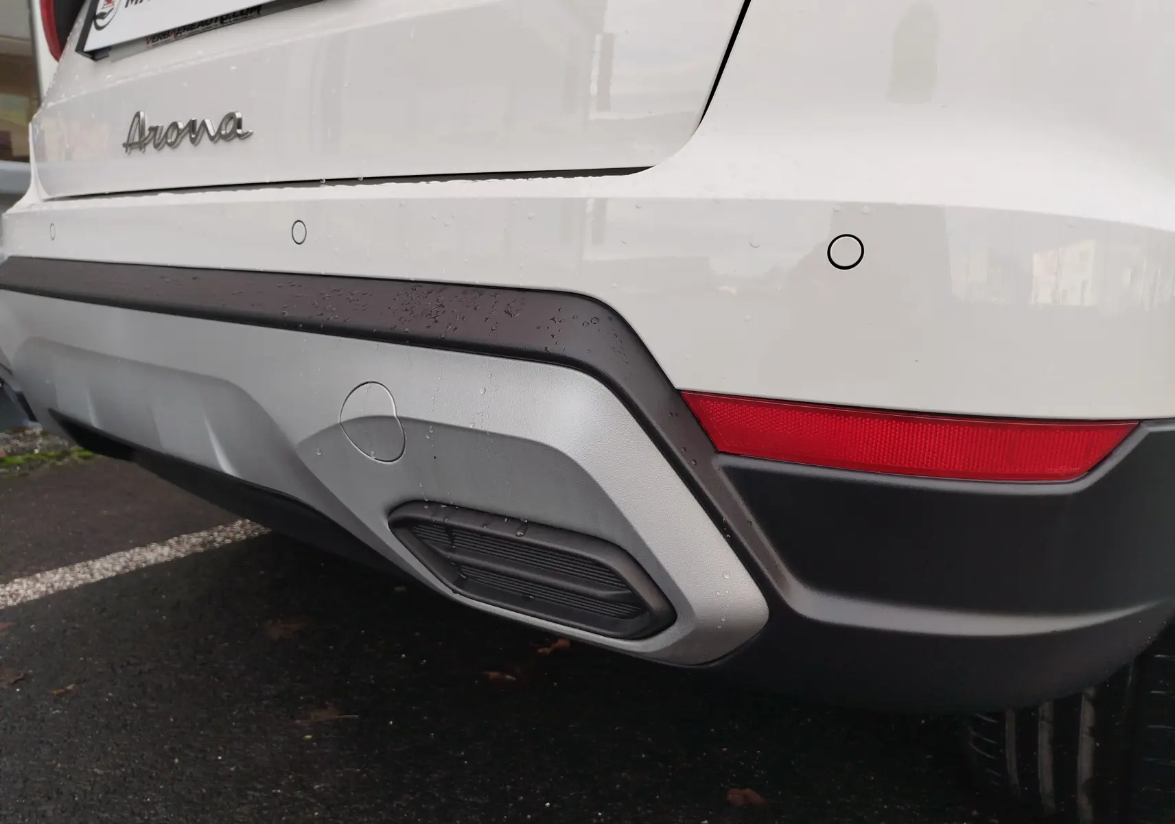 Vue rapprochée du coin arrière droit blanc candy d’un SEAT Arona 2023 avec feux rouges et pare-chocs noir et gris.